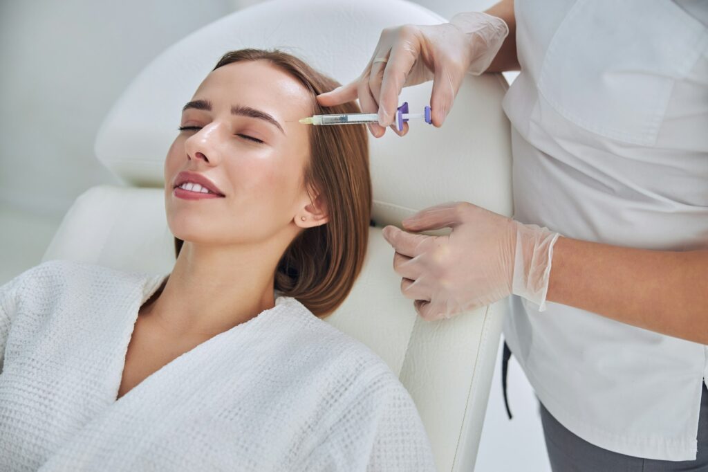 Patiente en peignoir recevant une injection sur le visage